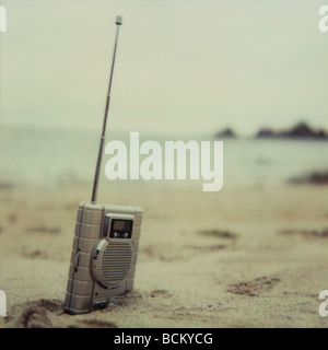 Radio à moitié enfoui dans le sable sur la plage Banque D'Images