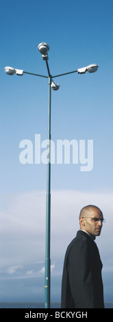 Homme debout près d'un lampadaire, looking over shoulder Banque D'Images