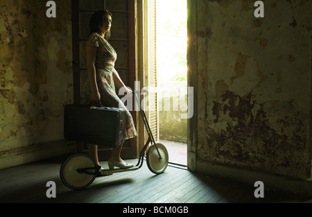 Femme debout par porte sur un scooter, holding suitcase Banque D'Images