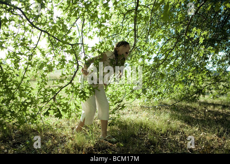 Fille de marcher sous les branches, jusqu'à la bouche grande ouverte, pleine longueur Banque D'Images