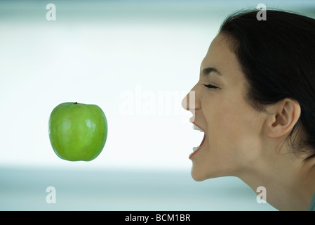 Flottant dans l'air, Apple woman reaching for elle avec la bouche ouverte, les yeux fermés Banque D'Images