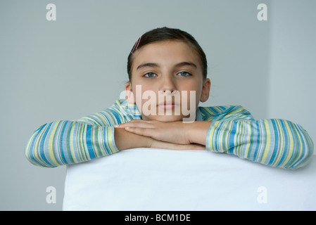 Preteen girl resting chin on hands, looking at camera Banque D'Images