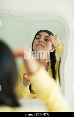 Jeune femme à la recherche de miroir, mise sur le maquillage, l'accent sur miroir Banque D'Images