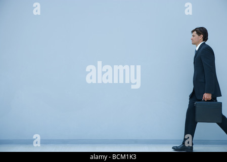 Businessman carrying briefcase, pleine longueur, side view Banque D'Images