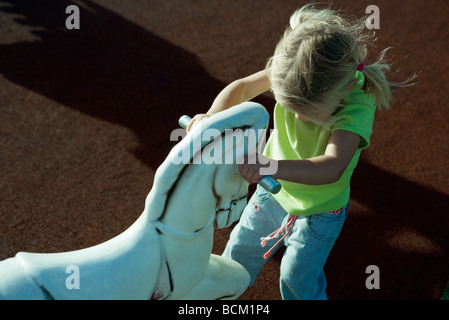 Girl standing in front of Rocking Horse, poignées de maintien, high angle view Banque D'Images