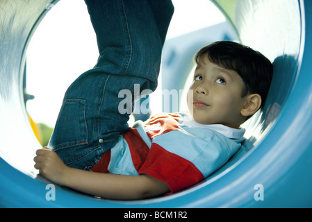 Garçon couché dans aire de tunnel avec les jambes, looking up, Close-up Banque D'Images