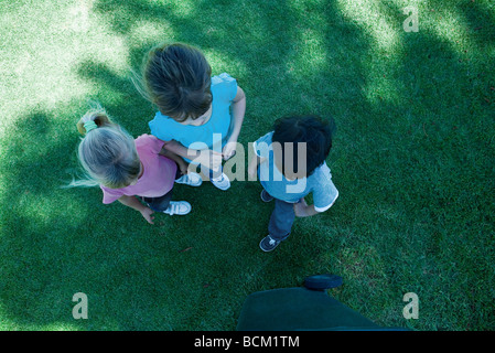 Trois enfants debout sur l'herbe, à l'ombre, vue à partir de juste au-dessus Banque D'Images