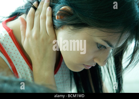 Close-up of woman holding le cou, regardant vers le bas Banque D'Images