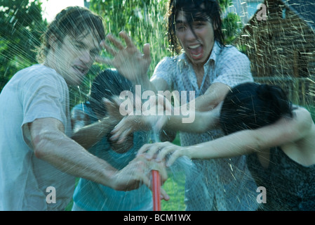 Jeunes amis d'avoir de l'eau lutte avec tuyau de jardin Banque D'Images