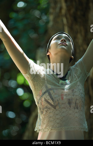 Young woman standing outdoors with arms raised, tête en arrière, jusqu'à Banque D'Images