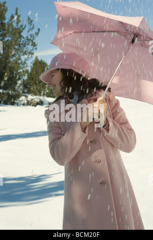 Teenage Girl standing under umbrella in snow, looking away Banque D'Images