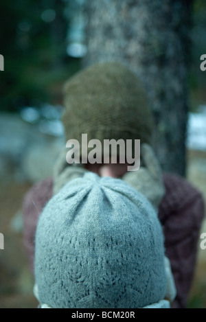 Deux amis debout face à face, les deux portant des chapeaux d'hiver, visages masqués Banque D'Images