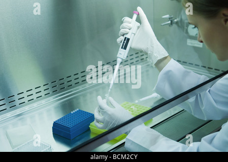 Female scientist dragées tube à essai en laboratoire, side view Banque D'Images