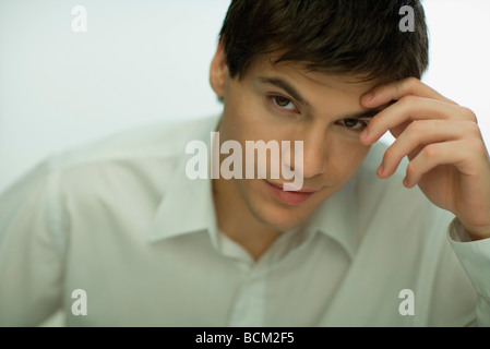 Jeune homme tenant tête, looking at camera, portrait Banque D'Images