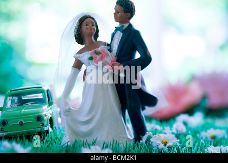 Plastic Bride and Groom standing in field de fausses fleurs, petite voiture en arrière-plan Banque D'Images