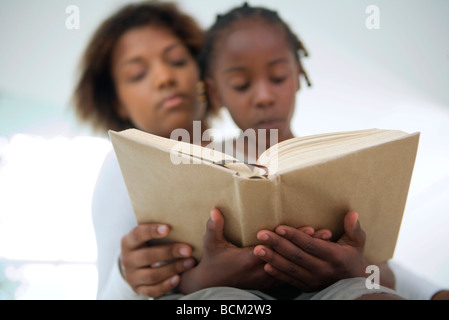 Young woman and girl reading book together, low angle view Banque D'Images