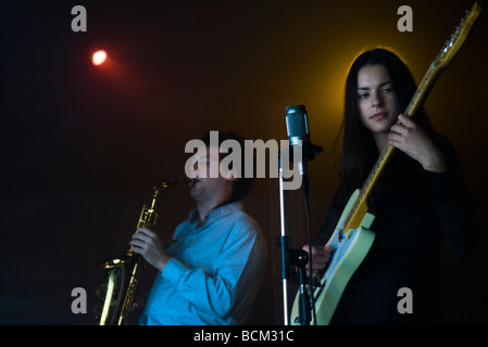 De jeunes musiciens jouant une guitare électrique et le saxophone dans night club Banque D'Images