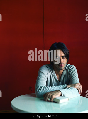 L'homme assis à table avec les mains sur le livre Banque D'Images