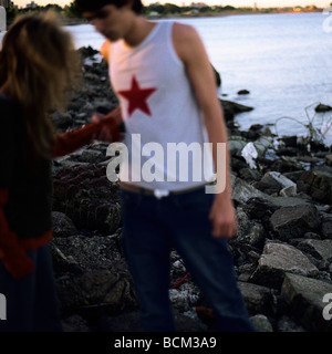 Jeune couple debout sur un rivage rocailleux Banque D'Images