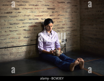 Young woman sitting on floor holding stuffed animal Banque D'Images