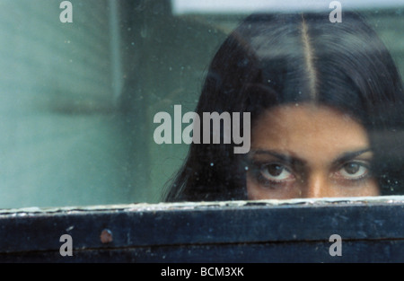 Mystérieuse femme peeking sur rebord de la fenêtre pour regarder à travers at camera Banque D'Images