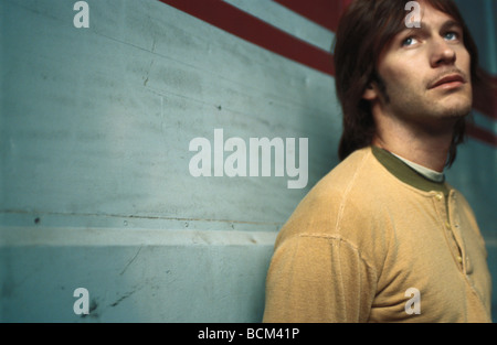 Young man looking up, leaning against wall Banque D'Images