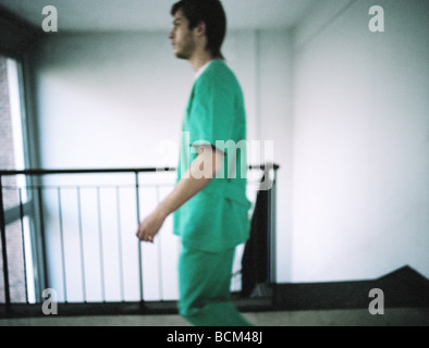 Infirmier l'walking down corridor en face d'escalier, side view Banque D'Images
