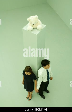 Couple standing contre piédestal avec ours en haut, tenant les mains, high angle view Banque D'Images