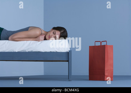 Femme endormie sur le lit, souriant, panier à proximité Banque D'Images