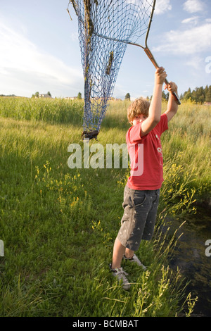 Garçon de dix ans faire son filet pour montrer une langouste qu'il a capturé dans un ruisseau, le sud du Colorado, USA Banque D'Images