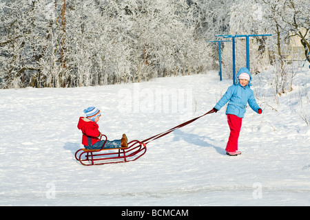 Heureux petite fille et garçon sur hiver neige cour couverte Banque D'Images