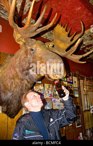 L'homme se nourrit d'une bière à un trophée orignal sur le mur à l'étoile filante tricorps à Huntsville dans l'Utah. Banque D'Images