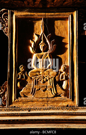 Relief en bois de boudha du Laos illuminée par la lumière du lever Banque D'Images
