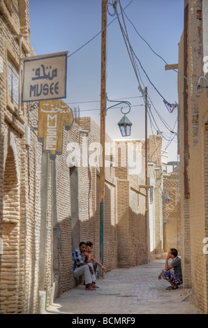 Trois hommes assis dans une ruelle à Tozeur, Tunisie, 14e siècle Ouled El Hadef trimestre. Banque D'Images