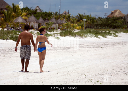 Jeune couple marche main dans la main sur le sable blanc de l'Île de Holbox, Quintana Roo, Yucatán, Mexique, Banque D'Images