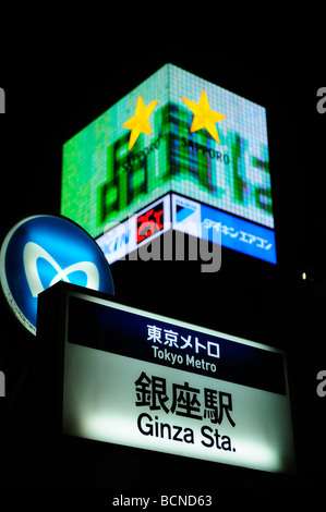 Signe de métro avec des écrans publicitaires en arrière-plan dans Ginza Tokyo Japon Banque D'Images