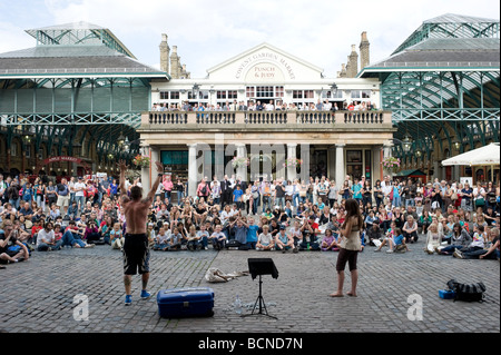 Un artiste de rue effectue à une grande foule de touristes à Covent Garden, Londres. Banque D'Images