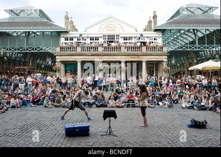 Un artiste de rue effectue à une grande foule de touristes à Covent Garden, Londres. Banque D'Images