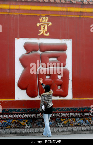 Jeune femme chinoise touch le géant 'Fu' personnage de bénédiction dans le Temple Zhaojue, Chengdu, province du Sichuan, Chine Banque D'Images