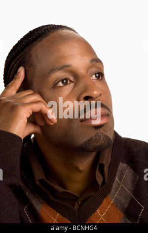 African American man dans 20-30's penser et avait la main sur le côté du visage. Sa tenue vestimentaire est décontractée et look classique avec pull marron. Banque D'Images