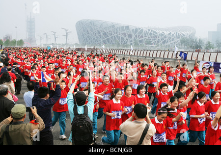 Les gens de Pékin exécutant passer le nid d'oiseau pendant une Bonne Chance Beijing Marathon, Beijing, Chine Banque D'Images