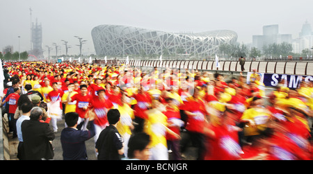 Les gens de Pékin exécutant passer le nid d'oiseau pendant une Bonne Chance Beijing Marathon, Beijing, Chine Banque D'Images