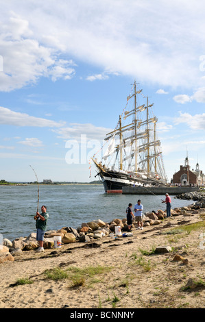 Les gens pêchent le long de Cape Cod Canal avec Kruzenshtern grand voilier amarré au Massachusetts Maritime Academy, Buzzards Bay, MA USA Banque D'Images