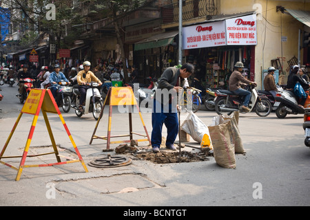 Workman creuser dans road Hanoi Vietnam Banque D'Images