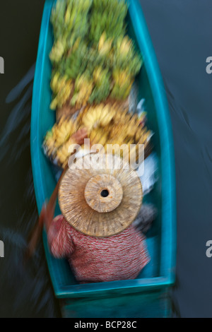 Une femme pagayer un bateau chargé de bananes au marché flottant de Damnoen Saduak, Bangkok, Thaïlande Banque D'Images