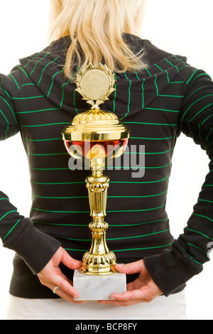 Junge Frau dans Sportkleidung hält einen Pokal image hinter in Ihrem Rücken Banque D'Images