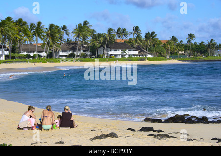 Les jeunes femmes et les jeunes enfants assis sur Sheraton Kauai Poipu Beach HI Banque D'Images