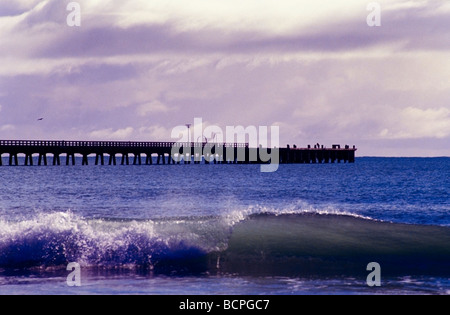 Tolaga Bay avec quai par petite vague se brisant sur la plage au premier plan Côte Est de la Nouvelle-Zélande Banque D'Images