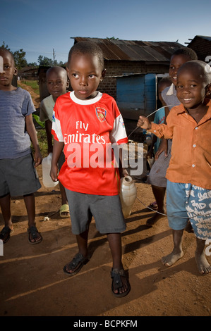 Jeune garçon en maillot Arsenal Football Club dans les rues dans des taudis ougandais Banque D'Images