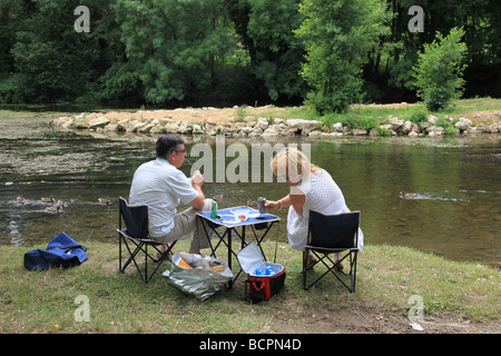 Vieux couple avoir un pique-nique sur la rivière Gartempe en France Banque D'Images